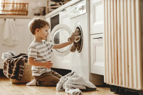 Szczęśliwy gospodarz chłopiec w pralni z pralką — Zdjęcie stockowe