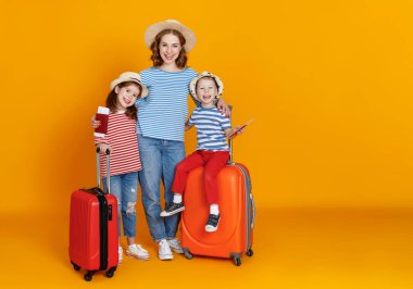 İyi yolculuklar! Gezginler ailesi çantalı anne ve çocuklar... biletleri ve pasaportları renkli sarı arka grupta.