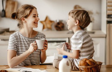 Aile kahvaltısı hazırlıyorum. anne ve çocuk ekmek keser ve sabah süt ile kurabiye yerler.
