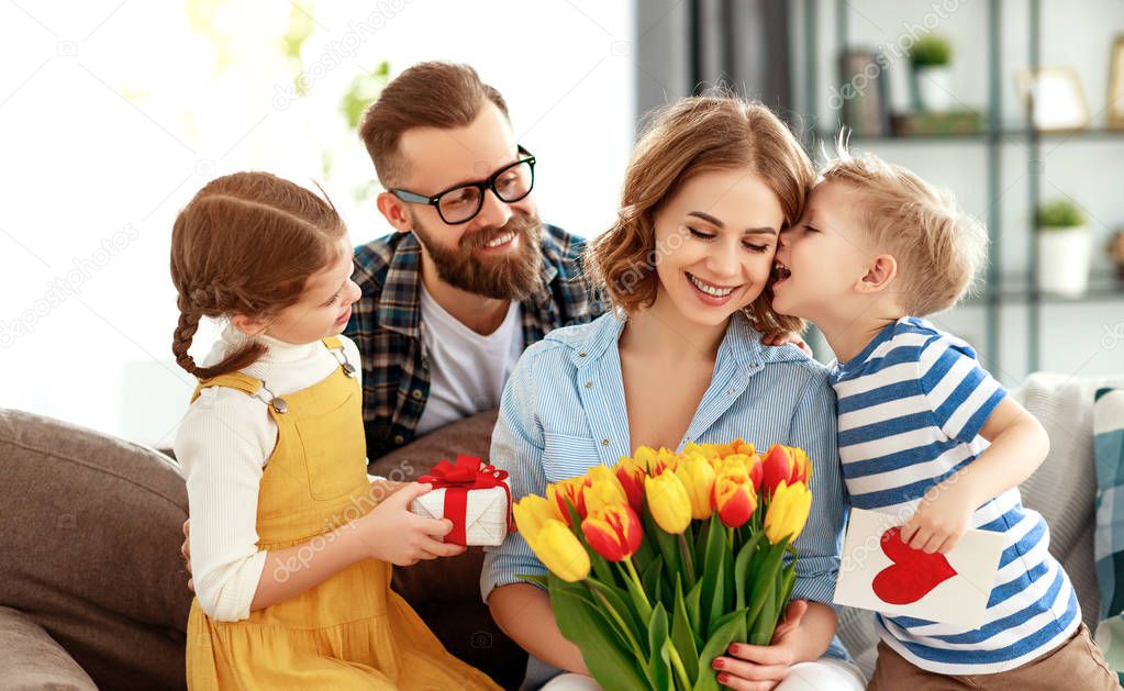 happy mother's day! father and children congratulate mother on holiday and give flower