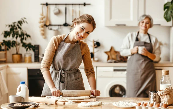 happy family grandmother  old mother mother-in-law and daughter-in-law daughter cook in kitchen, knead dough and bake cookie