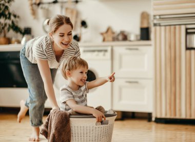 Mutlu aile annesi, ev hanımı ve oğlu çamaşır makinesiyle çamaşır yıkıyor.
