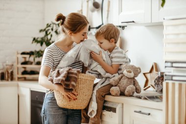 Mutlu aile annesi, ev hanımı ve oğlu çamaşır makinesiyle çamaşır yıkıyor.