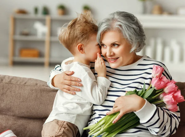 Söt Liten Pojke Viskar Till Glad Senior Mormor Sitter Soffan — Stockfoto