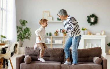 Hafta sonunu evde birlikte geçirirken kanepede gülümseyen ve dans eden son sınıf öğrencisi bir kadın.