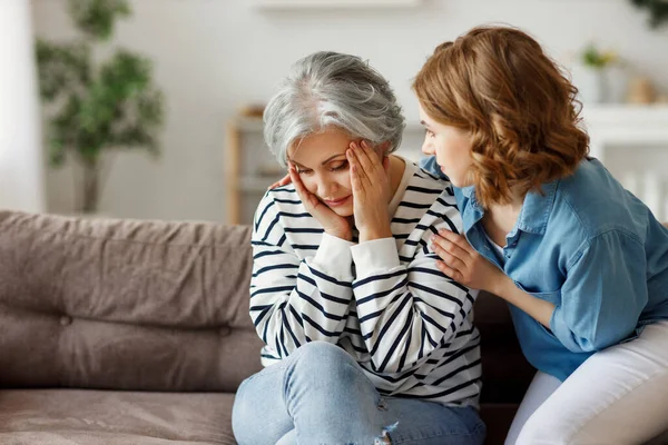 Young Woman Hugging Comforting Sad Senior Mother While Sitting Couch — Stock Photo, Image