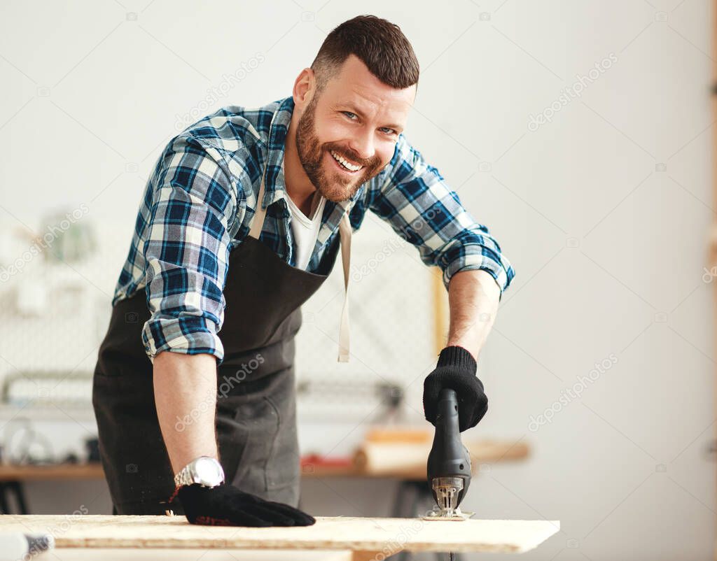 young happy male carpenter    working in a worksho