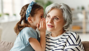 Küçük kız evde birlikte kanepede otururken şaşkın yaşlı kadının kulağına gizlice fısıldıyor.