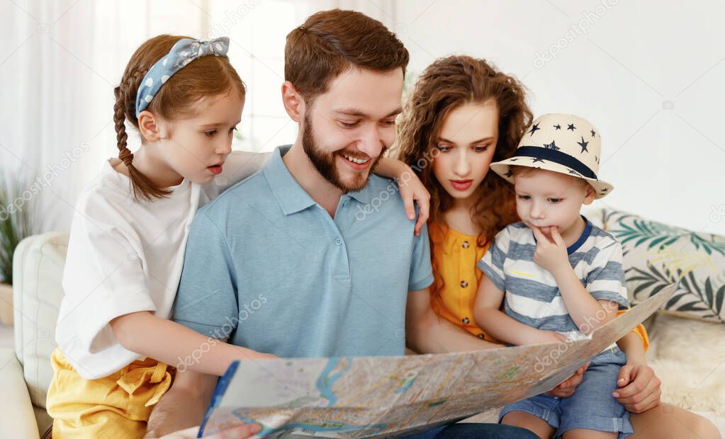 Laughing parents with little daughter and son exploring map together while making up new trip for summer vacatio