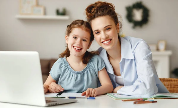 正の若いです女性を助ける娘で情報を検索するための宿題インターネット上で一緒に座っている間にテーブルとノートパソコンで自宅 — ストック写真
