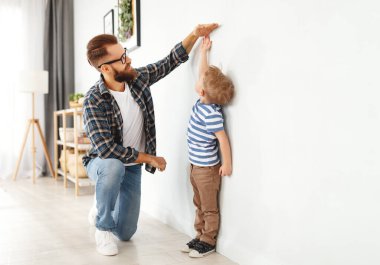 Gelişim konsepti, büyüme. Bir baba, çocuğunun boyunu ölçer.