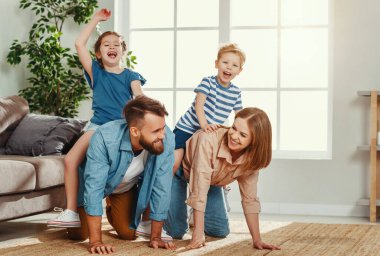 Neşeli genç çift gülüyor ve birbirlerine bakıyorlar. Bu arada eğleniyorlar ve mutlu, aktif çocukları sırtımda taşıyorum.