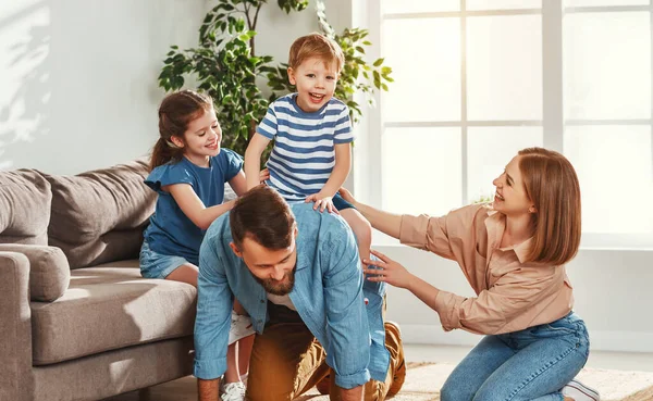 家族と時間を過ごしながら一緒に家で楽しい時間を過ごしながら興奮した息子にピギーバックライドを与える陽気な若い男 — ストック写真