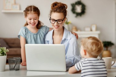 Mutlu bir aile. Uzaktan kumandalı bir bilgisayar başında çalışan serbest çalışan bir anne. Eğlenceli çocuklarda, evde oğulları ve kızları var.