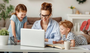 Mutlu bir aile. Uzaktan kumandalı bir bilgisayar başında çalışan serbest çalışan bir anne. Eğlenceli çocuklarda, evde oğulları ve kızları var.