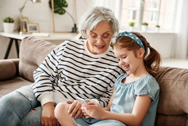 Liten Flicka Ler Och Visar Smartphone För Äldre Kvinna När — Stockfoto