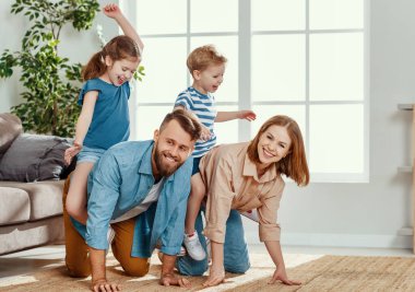 Neşeli genç çift gülerken aynı zamanda eğleniyor ve mutlu, aktif çocuklara kucak açıyor.