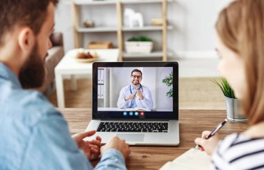 Genç adam ve kadın notlar alıyor ve dost psikoloğu dinlerken evden kliniğe video çağrısı yapıyor.