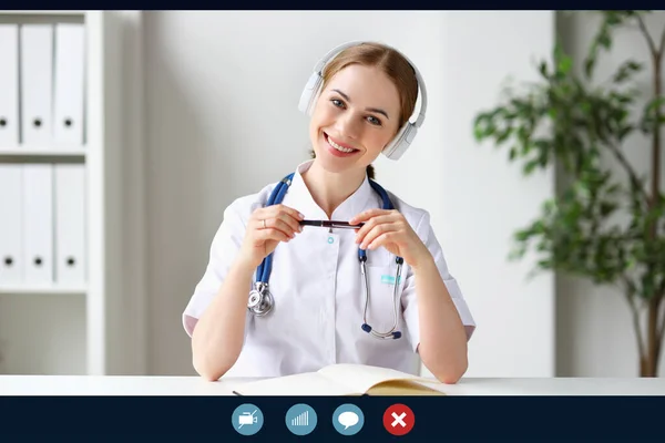 Cliniのオフィスからのビデオ通話に応答しながら カメラのための笑顔ヘッドフォンで積極的な女性医療従事者 — ストック写真