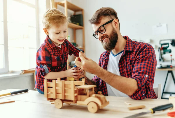 Счастливый Маленький Мальчик Помогает Отцу Создавая Деревянный Игрушечный Автомобиль Рабочем — стоковое фото