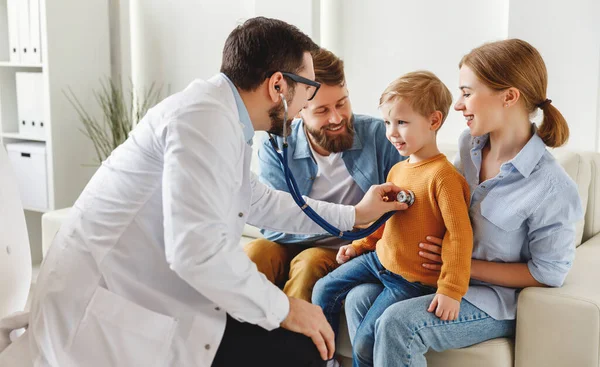 Friendly medical practitioner using stethoscope on chest of happy boy during family visit in cozy office in modern clini