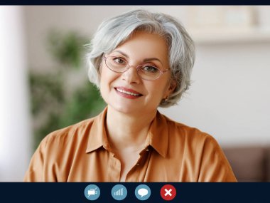  Mutlu yetişkin büyükanne video konuşmasında web kamerası konferansını kullanarak karantinada konuşuyor.