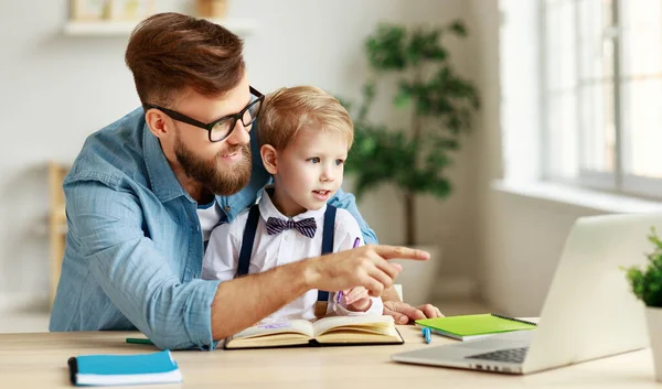 家で一緒にオンライン学習中に小さな息子へのレッスンを説明しながら ノートパソコンを指して眼鏡の若いひげを生やした男 — ストック写真