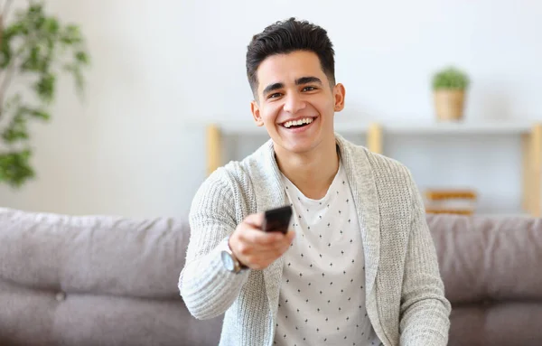 Happy Young Ethnic Guy Smiling Changing Channels Remote Control While — Stock Photo, Image