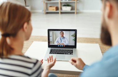 Genç adam ve kadın notlar alıyor ve dost psikoloğu dinlerken evden kliniğe video çağrısı yapıyor.