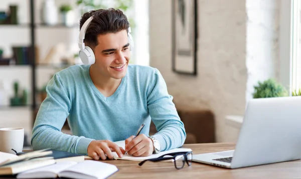 Gelukkige Etnische Man Koptelefoon Glimlachen Schrijven Notebook Terwijl Zitten Aan — Stockfoto