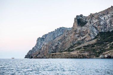 Dağın yanındaki denizde bir gemi.