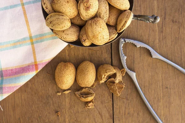 Group of arabic almonds in silver bowl  on a wooden table  with a nutcracker