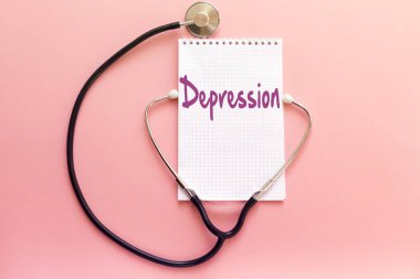 hastalığı depresyon kavramı el yazısı üstünde beyaz defter ve pembe bir arka plan üzerinde stetoskop
