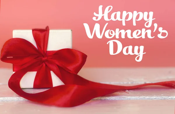 幸せな女性のテキストとピンクの背景の白い木製テーブルの上の細い赤いリボンと白い小さなギフト ボックス — ストック写真
