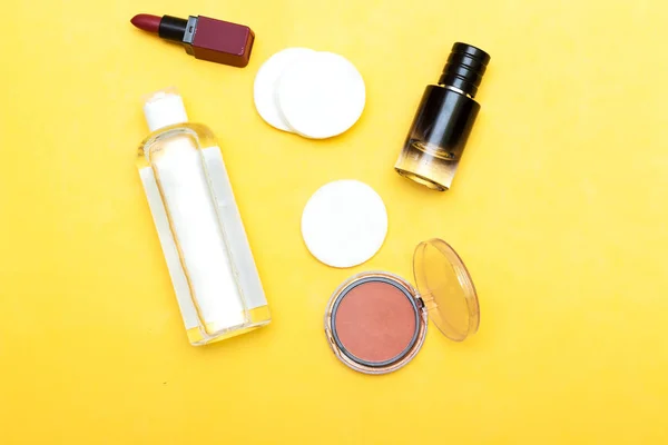 Makeup remove skin care. Tonic for face skin or makeup remover in a plastic bottle, cotton pads and  cotton buds on yellow background. bottle perfume and makeup