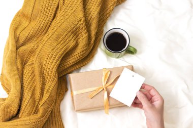 Kahve fincanı ve hediye, yatağın üstünde boş bir kart, merhaba kış konsepti.