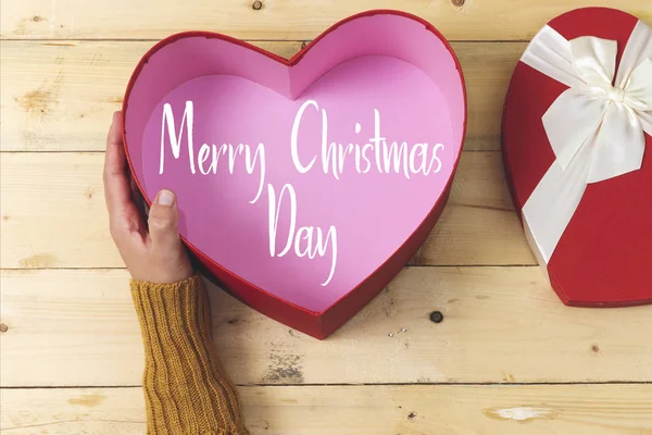 hand holding open heart shaped box on wood table