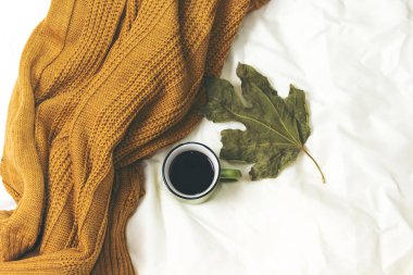 Yatakta yün eşarbın üstünde kahve fincanı, merhaba kış konsepti.