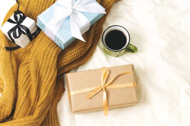 Kahve fincanı ve hediye kutuları, yatakta yün atkı, merhaba kış ve noel konsepti.