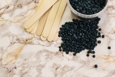 Tüy dökücü inci mavisi katı balmumu fasulye ve mermer zemin üzerinde ahşap sopa