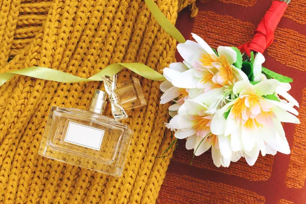 花の花束で飾られたカラーマスタード冬のスカーフの上に結び目カップとボトル香水 — ストック写真