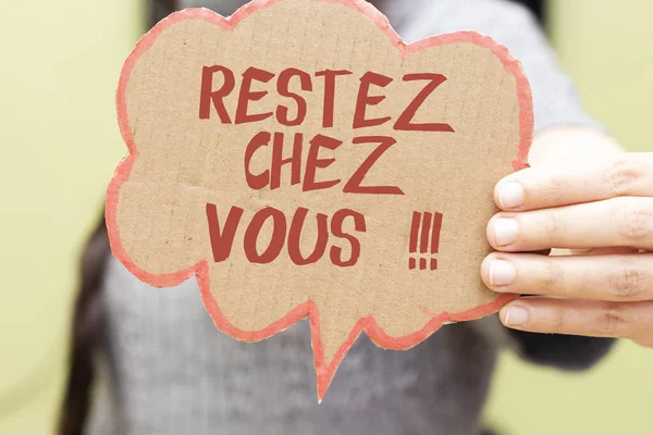亲密的女人手托着语卡泡 上面写着法语单词Restez Chez Vous被翻译成英语呆在家里 — 图库照片