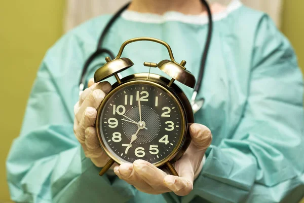 surgeon doctor woman  holding alarm clock showing 7 am or pm