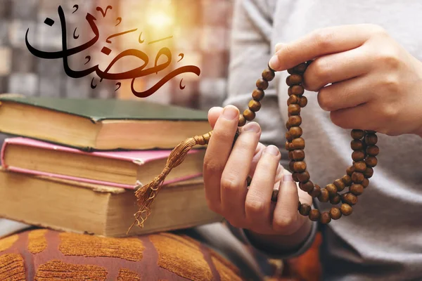 Muslim women using misbaha to keep track of counting in tasbih, Ramadan Mubarak. Translated: Happy & Holy Ramadan on white envelope. Month of fasting for Muslims.