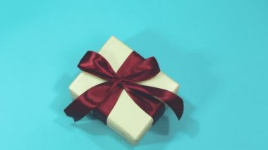 Elinde bir Noel hediyesi tutan kadın mavi arka planda izole edilmiş.