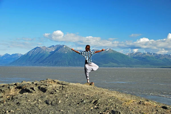 Man doing yoga at the coastline facing the mountains — Stock Photo, Image