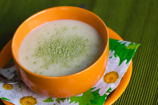 Turuncu kabın içinde rendelenmiş yeşil peynirli kremalı çorba