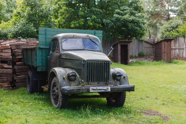 Ancient Soviet car in green meadow and old abandoned wooden outd — Stock Photo, Image