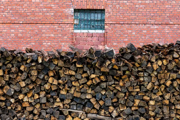 kırmızı tuğla duvara yığılmış ahşap yakacak odun