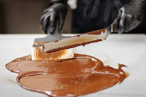 Кондитер в перчатках делает шоколад в форме
